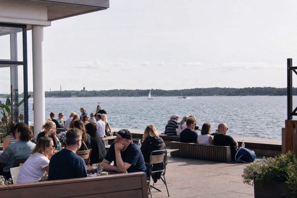 People relaxing on a sunny Helsinki seaside terrace on a mild summer day