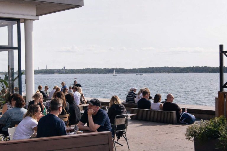 People relaxing on a sunny Helsinki seaside terrace on a mild summer day