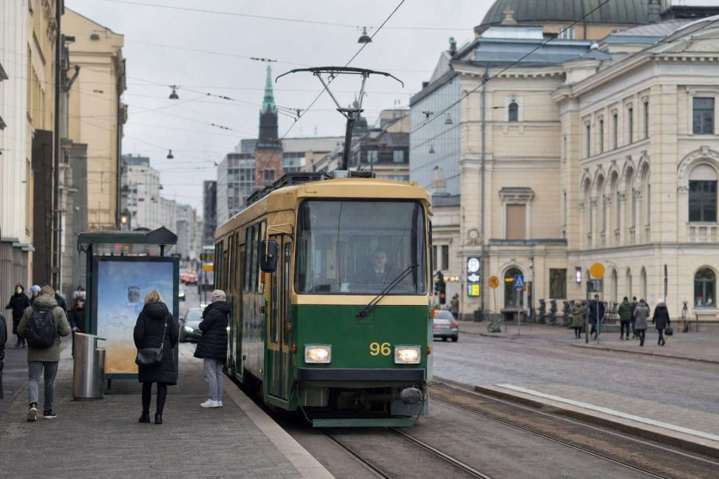 A green Helsinki tram on a downtown street on an ordinary day