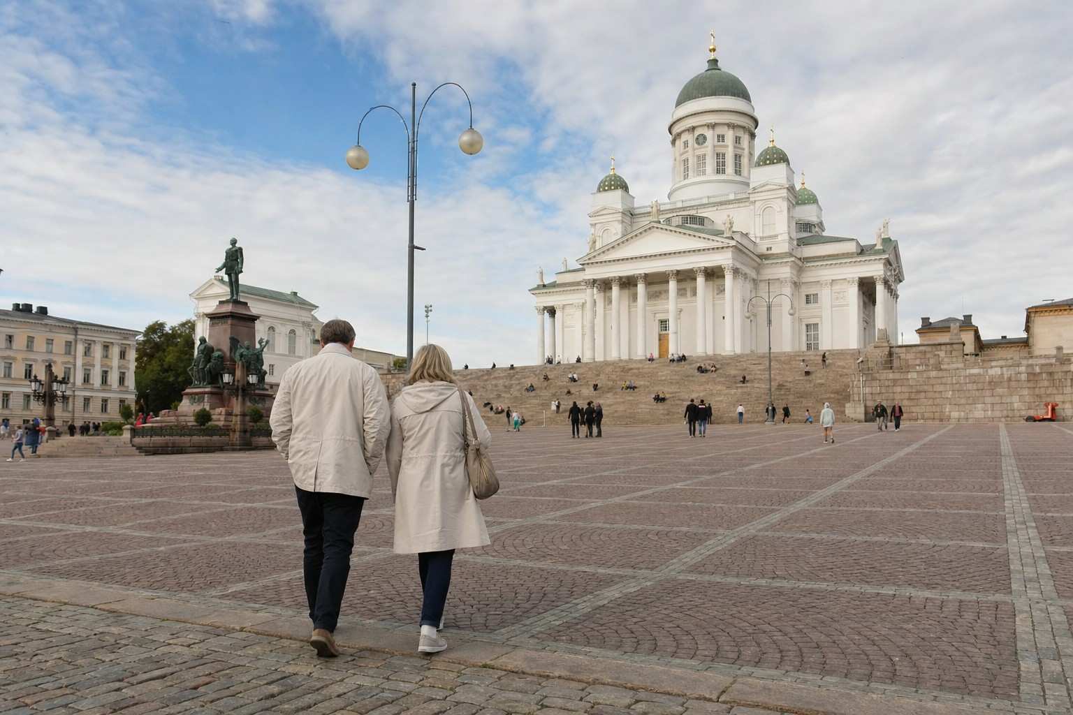 A couple walking across Senate Square toward Helsinki Cathedral in soft daylight