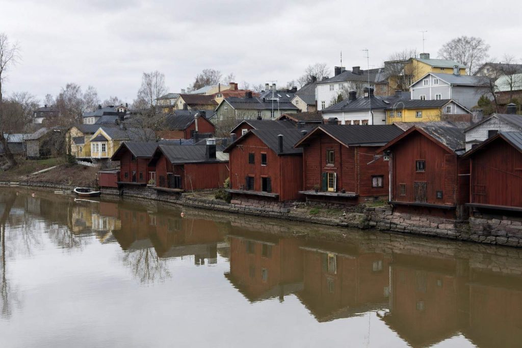 The red riverside warehouses of Porvoo old town reflected in the calm river